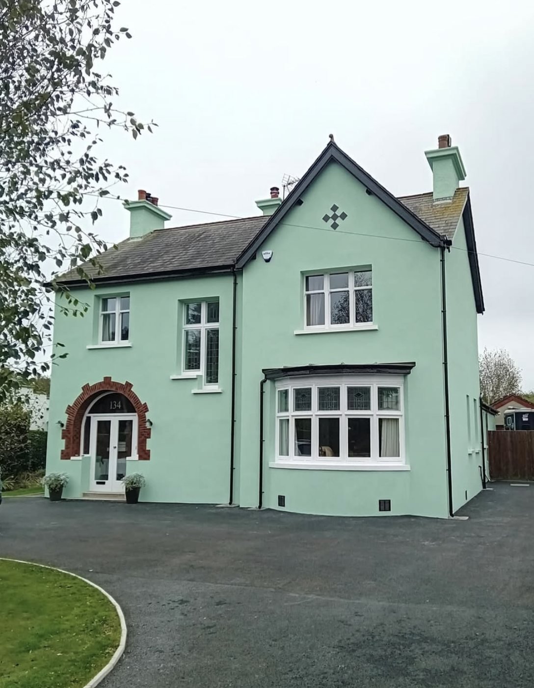 Detached house in a pale sage finish with the brick arch around the door kept