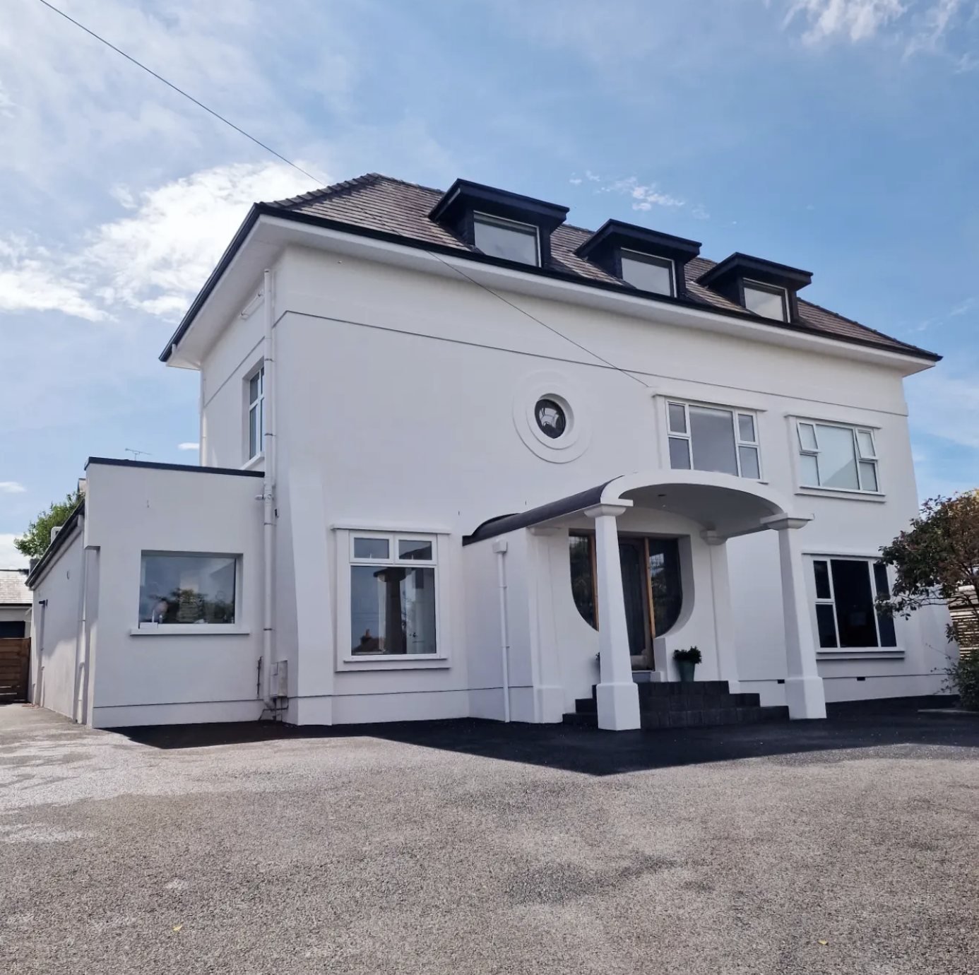 Detached house in white with a round window surround, curved canopy and dormers