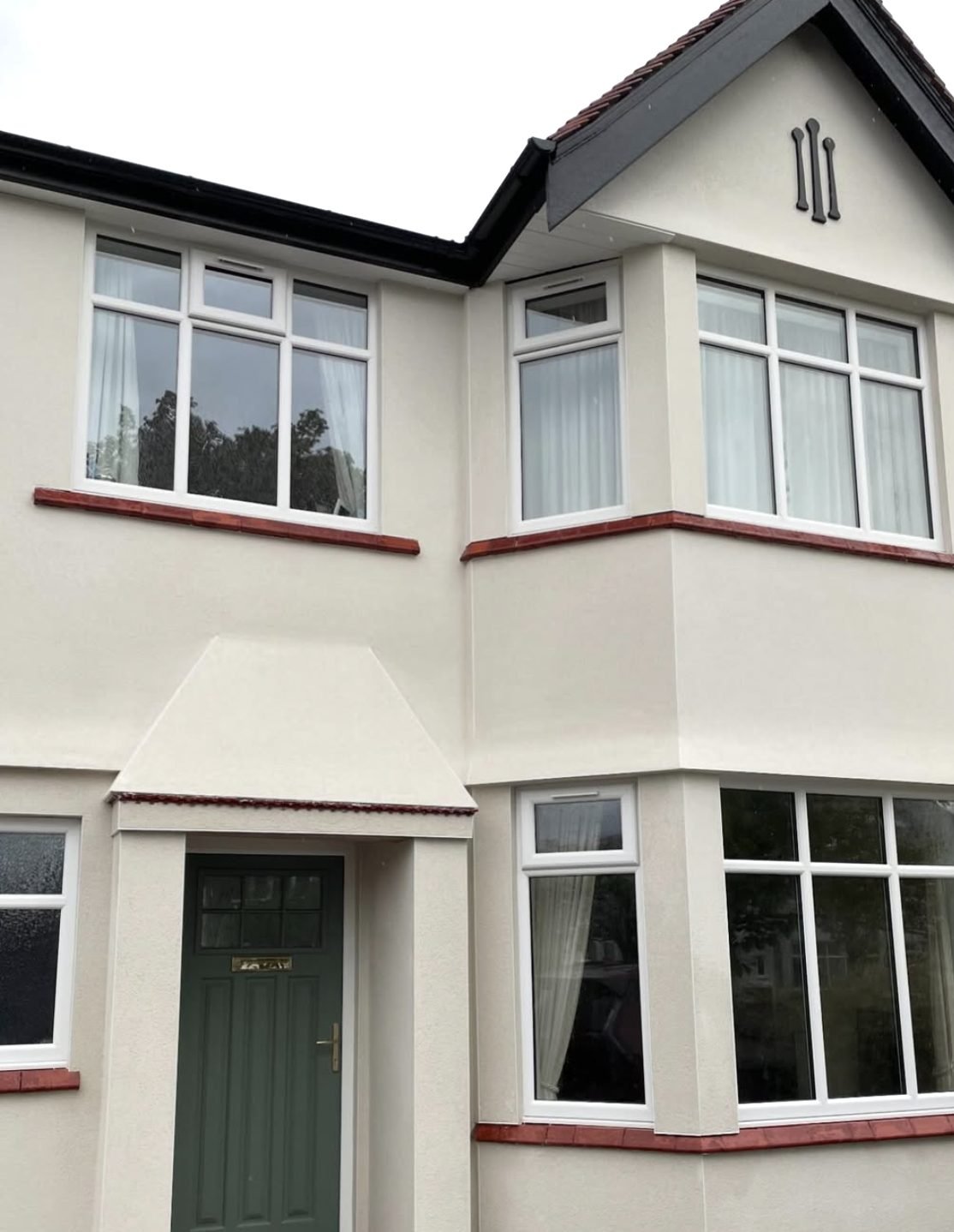 Interwar semi with curved bays in a cream finish and red tile sills